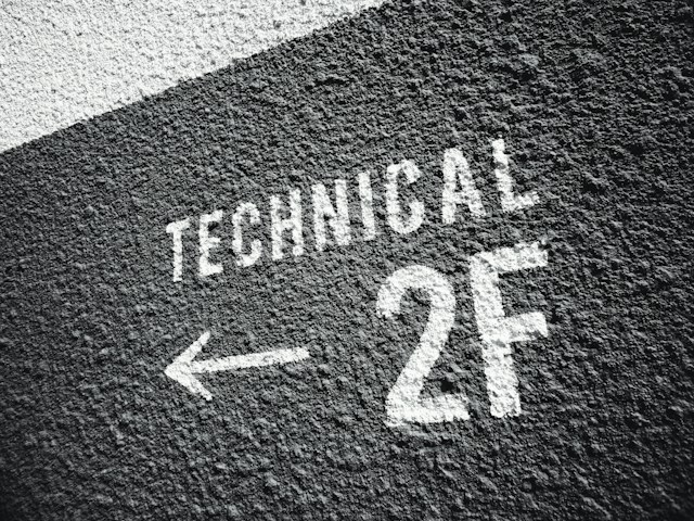 Un'immagine di una parete nera grezza con il testo "TECHNICAL 2F" dipinto in bianco.