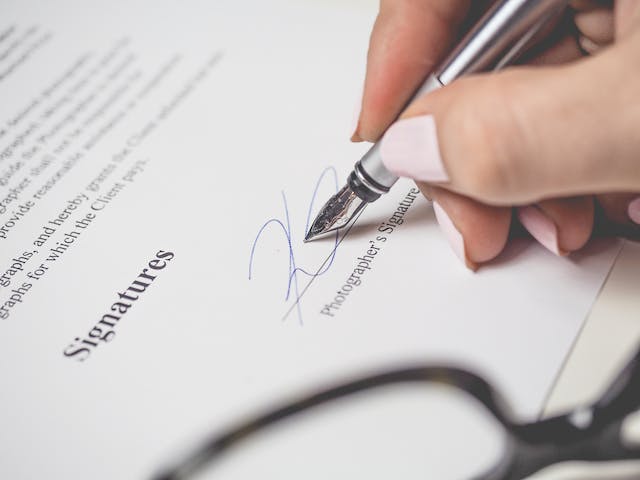 Un'immagine di una persona che appone la propria firma su un documento.