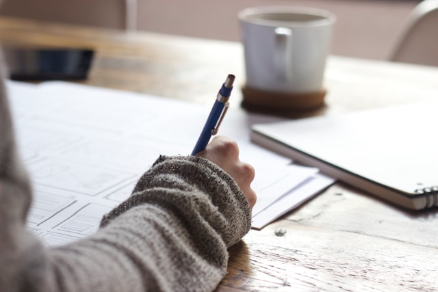 Una signora studia per un esame con una tazza di caffè sul tavolo