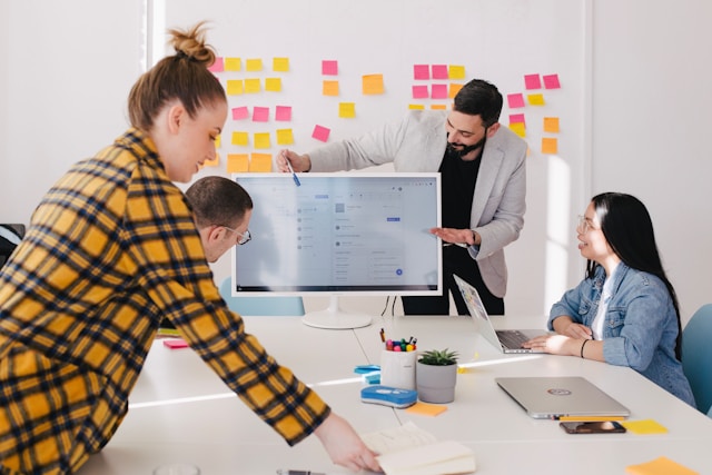 Le persone lavorano insieme in una sala riunioni con un grande computer. 
