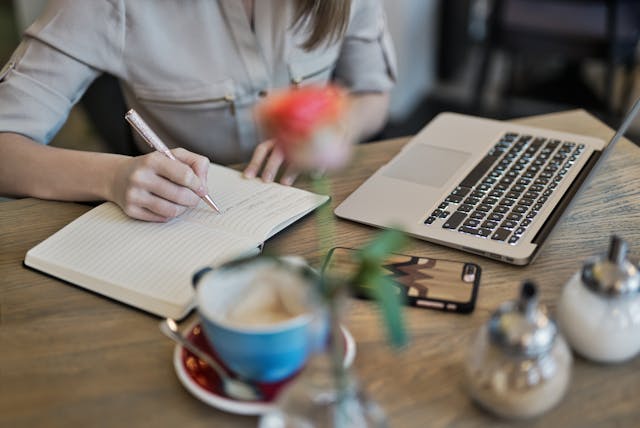 Qualcuno utilizza un computer portatile e scrive su un libro.