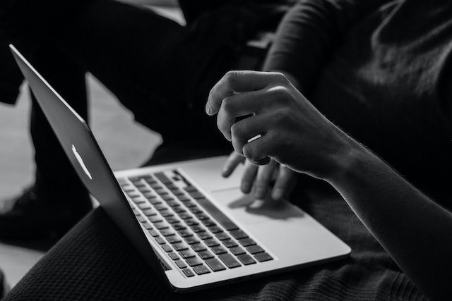 A black and white photograph of someone using their MacBook to find legal translation services.