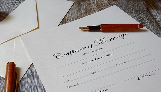 A blank marriage certificate and an open pen on a wooden table. 
