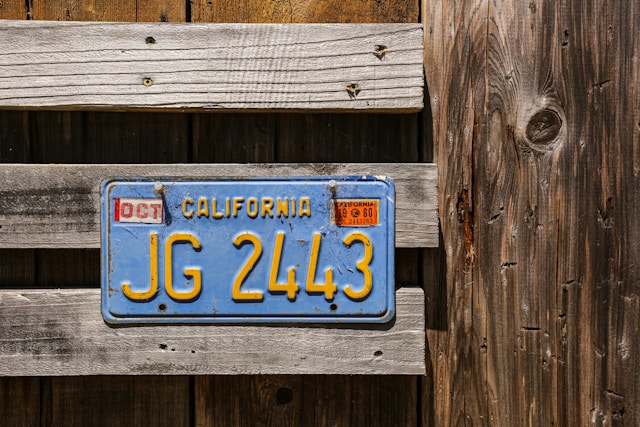 A California license plate nailed to a wooden fence.