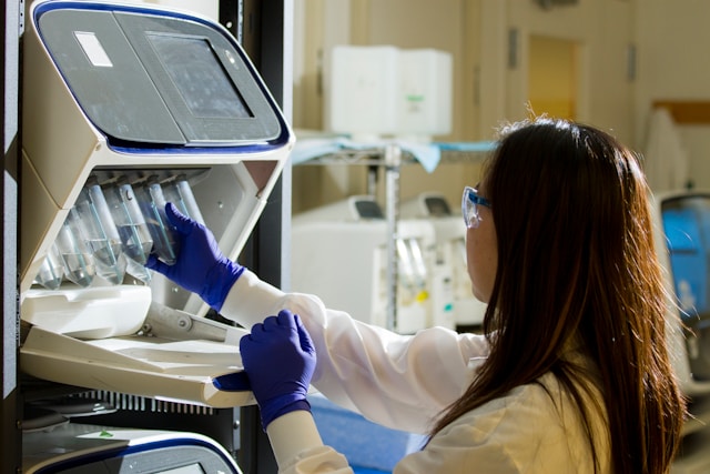 A woman attaches several test tubes to a machine.