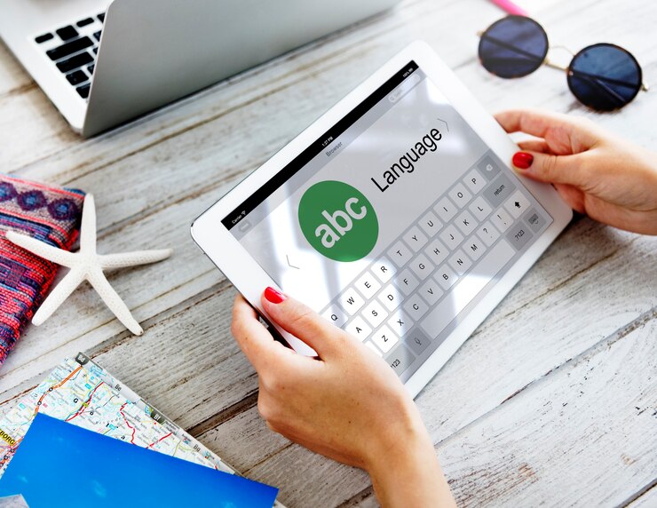 A person holds a tablet displaying “Abc Language” on the screen.