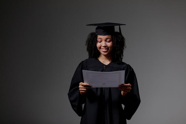 A person smiles at a certificate in their hand.
