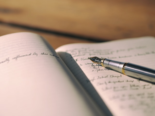 A close-up view of a pen placed on the page of an open book.