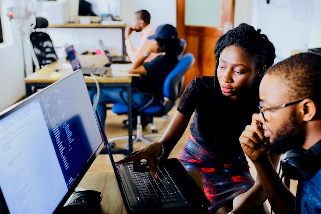 Two translators working in front of a desktop screen in an office. 