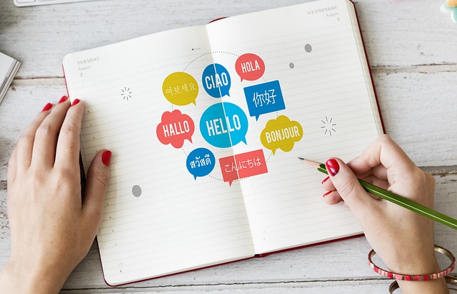 A hand writes “Hello” in different languages in an open book.