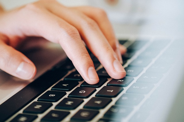 Close-up view of someone’s hand typing on a black keyboard.