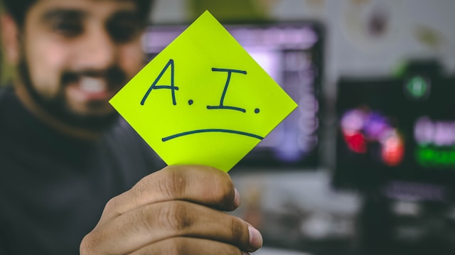 A person holds a green card with the inscription "AI."
