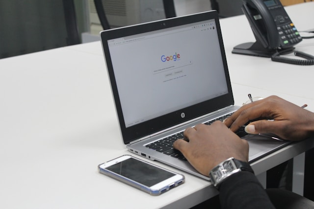 A person searches the internet through Google on a laptop. 
