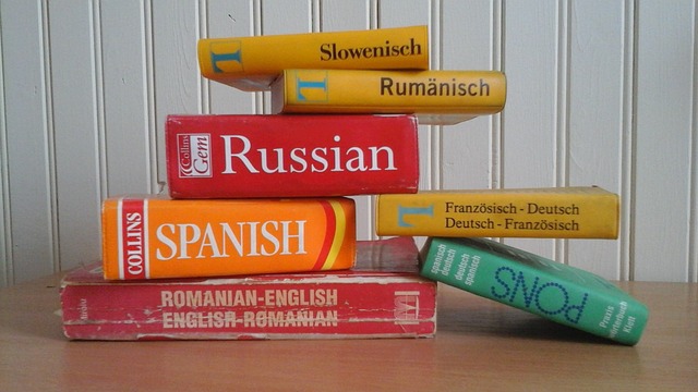 Several dictionaries of different languages stacked on top of one another.