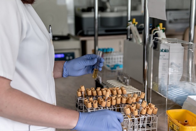 A person wearing a white scrub arranges test tubes in a rack inside a laboratory.
