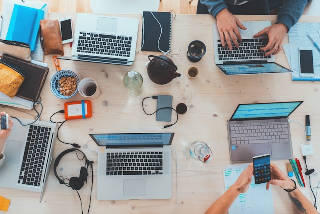 A team sits around a table and works on laptops.
