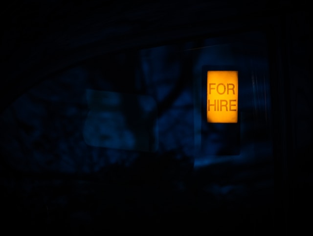 A lit sign on a dark background reads "For Hire."
