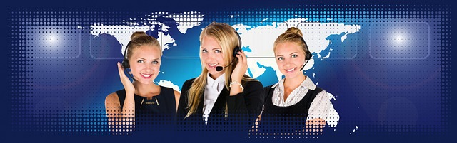 Three people wearing headsets stand before the world map.
