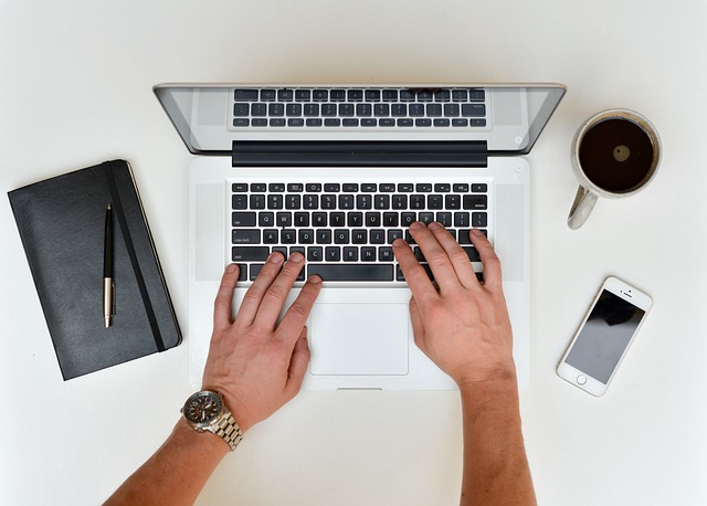 A person types on a PC on a work desk.