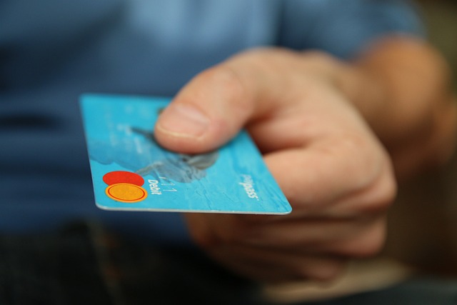 A person presents a blue credit card.
