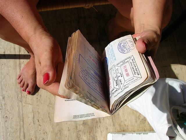 A person opens a passport book filled with visa stamps.