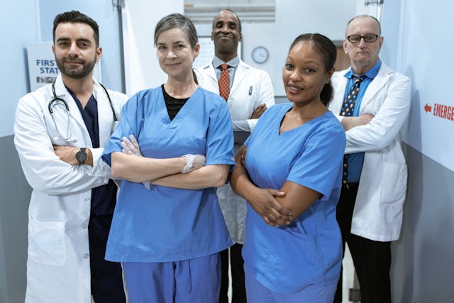 A group of medical practitioners in a hospital hallway.
