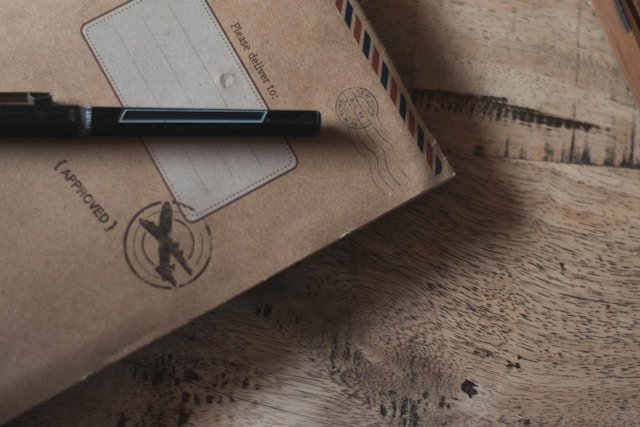 A brown envelope on a table with an approval stamp and a pen.
