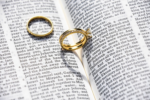 A pair of gold wedding rings is between an open book.