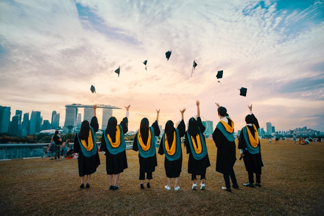 A group of graduating students throw their hats into the air. 
