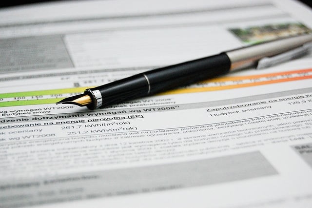 A black pen is on a printed document with highlighted texts.
