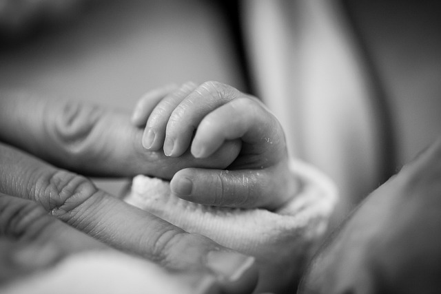 A baby clutches its mother’s finger.
