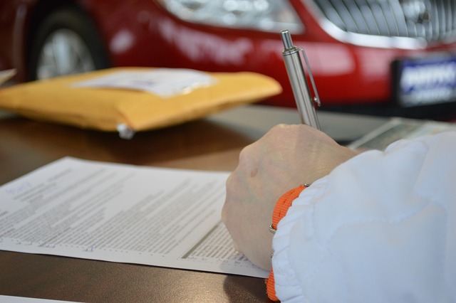 A person in a white shirt signs on a printed document.
