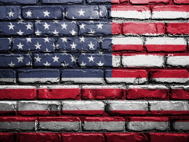 An American flag painting is on a brick wall.
