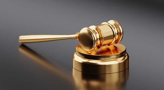 A gold gavel and hammer on a smooth gray surface.
