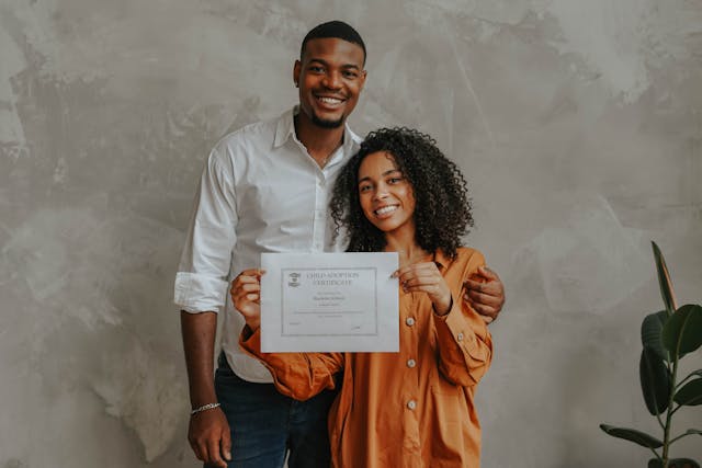 A couple holds an adoption certificate.