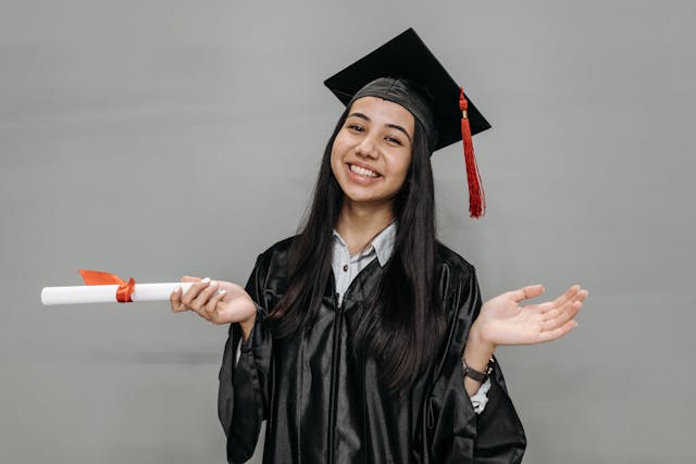 A graduate holds out their scroll as they pose for a picture.
