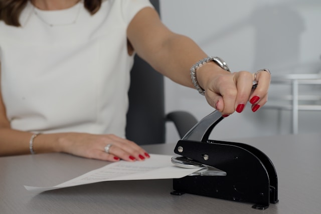 Someone in a white dress stamps a printed document.