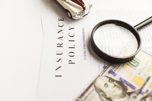 An insurance policy with a magnifying glass, a toy car, and a $100 bill.