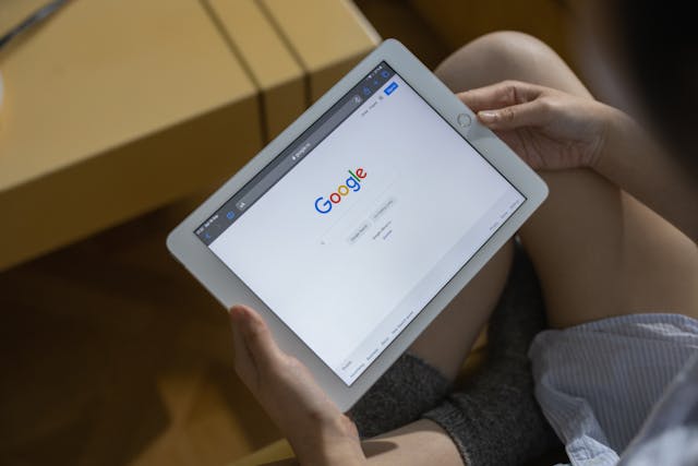 A person holds an iPad with the Google homepage open