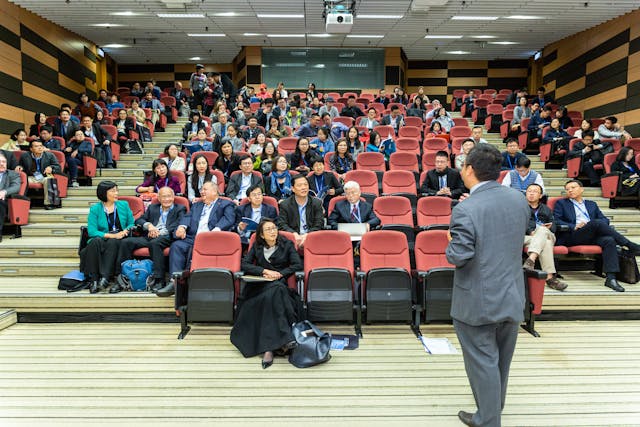 A person in a suit addresses a crowd.
