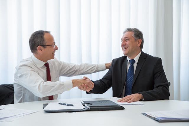 Two people shaking hands in a business environment.