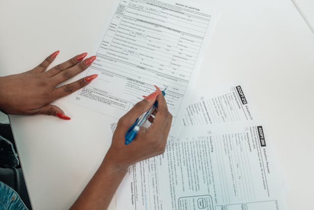 A person signs adoption papers on a desk.
