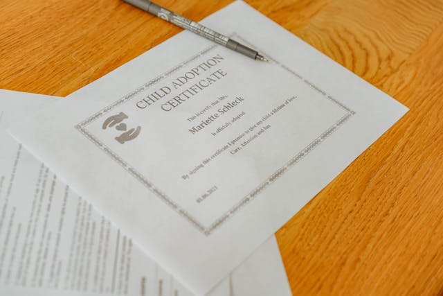 A child adoption certificate on a desk with a pen.